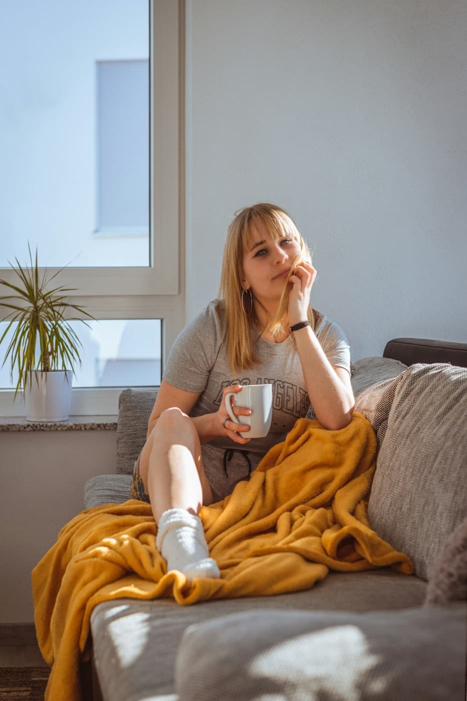 A person at ease at home with a warm drink, in soft natural light